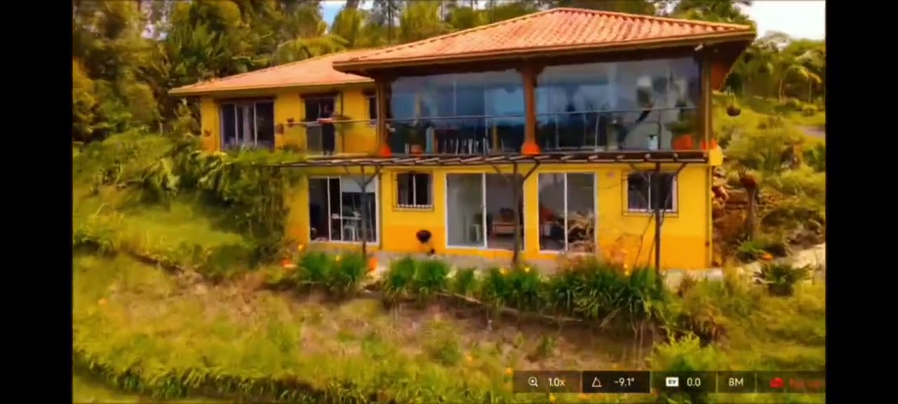 Fotograma del video: fachada amarilla de la casa, terraza y nivel inferior